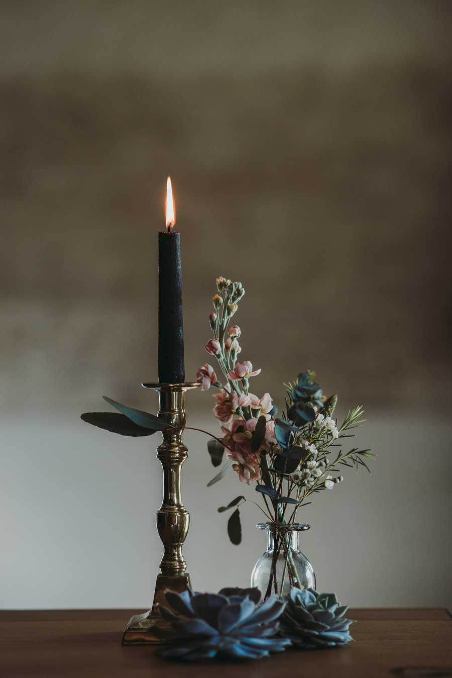 black candle and a vase with flowers