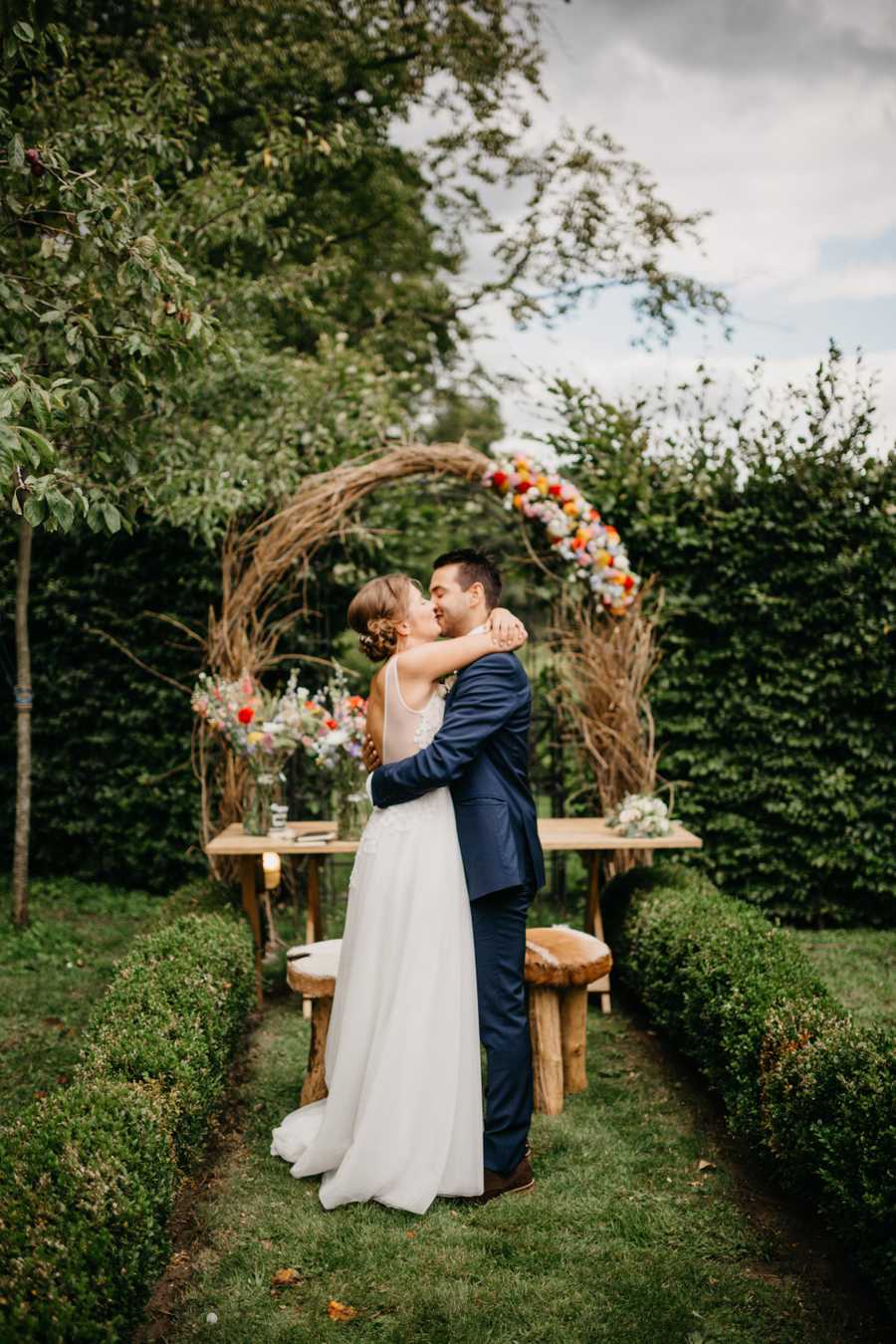 couple kissing in front of a wedding arch